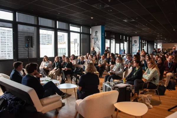 Salle de conférence comble avec vue sur les baies vitrées du stade