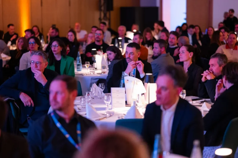 Public attentif assis à des tables lors d'une conférence en soirée